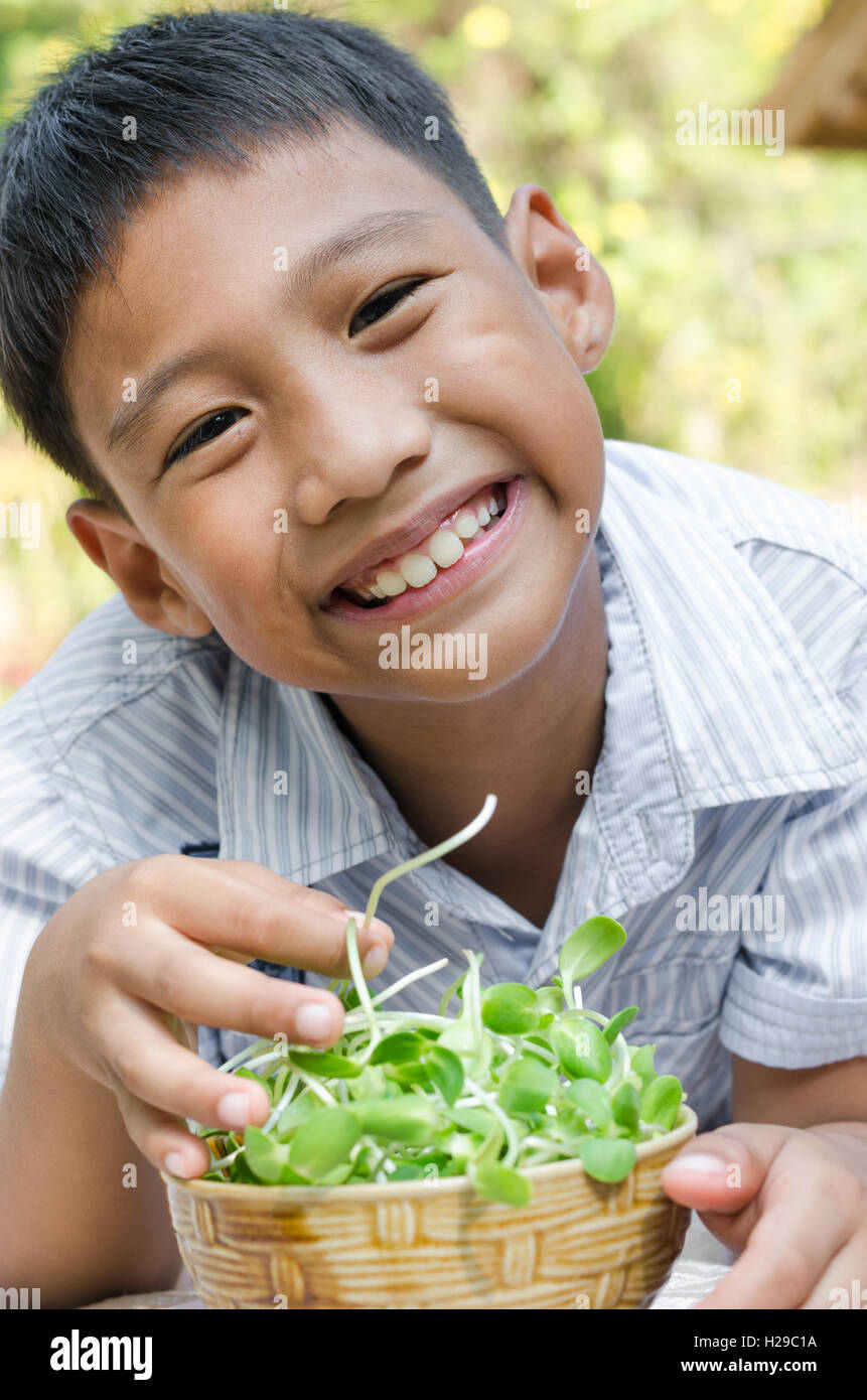 Asiatische Kind genießen, mit Gemüse (Sonnenblumen-Sprossen). Stockfoto