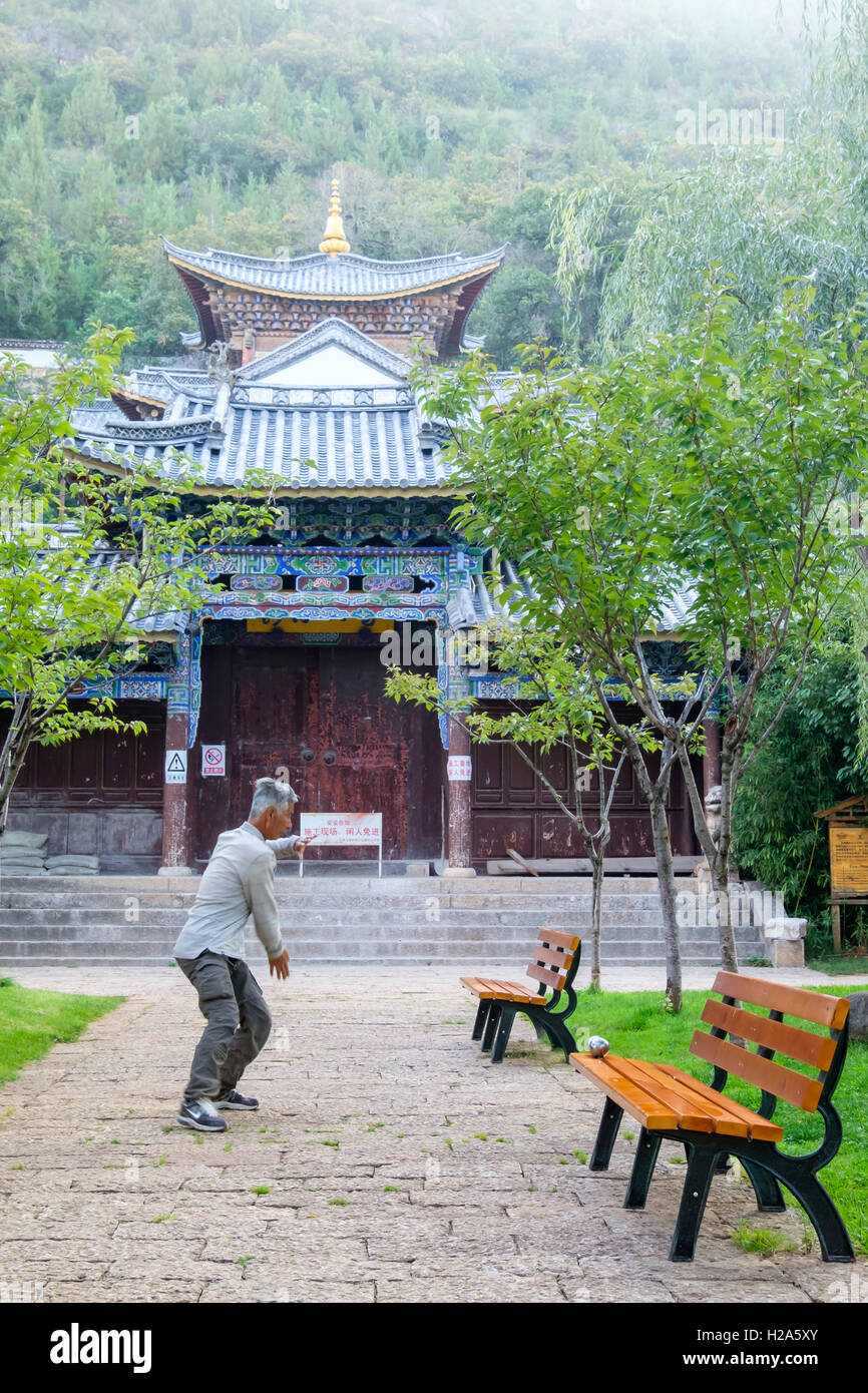 Orientalische älterer Mann üben Tai Chi in einem Park vor einem chinesischen Tempel in China Stockfoto