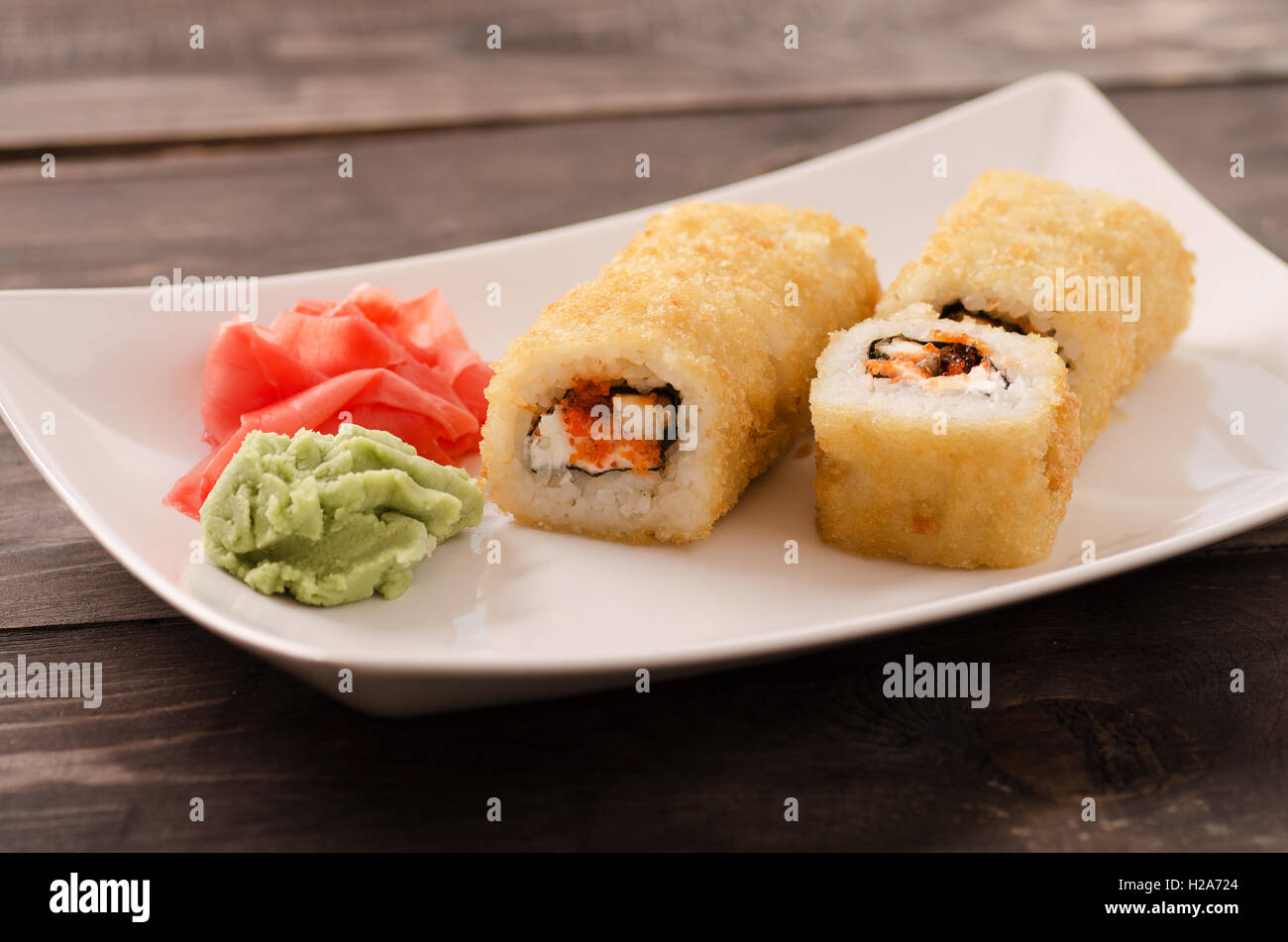 Japanische Fisch Sushi Rollen auf einem weißen Teller auf Holztisch Stockfoto