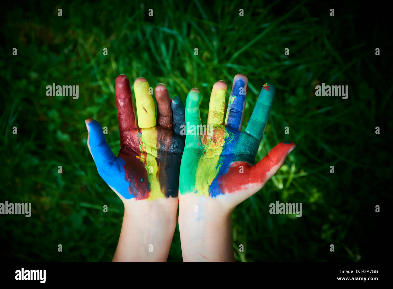 ein Kind mit den Fingern und Handflächen Farben malen. lustig und kreativ. Grasgrün Hintergrund Stockfoto