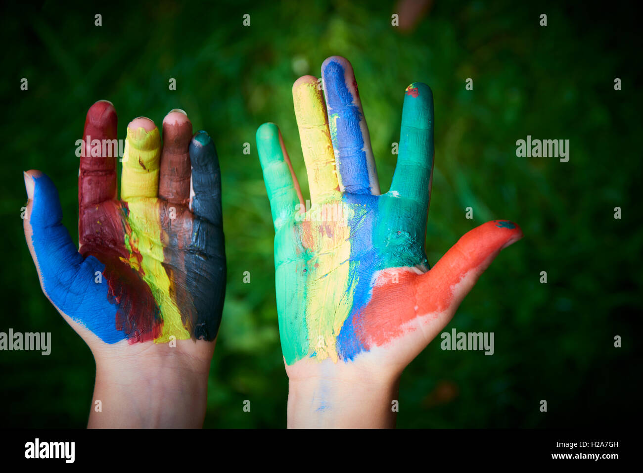ein Kind mit den Fingern und Handflächen Farben malen. lustig und kreativ. Grasgrün Hintergrund Stockfoto