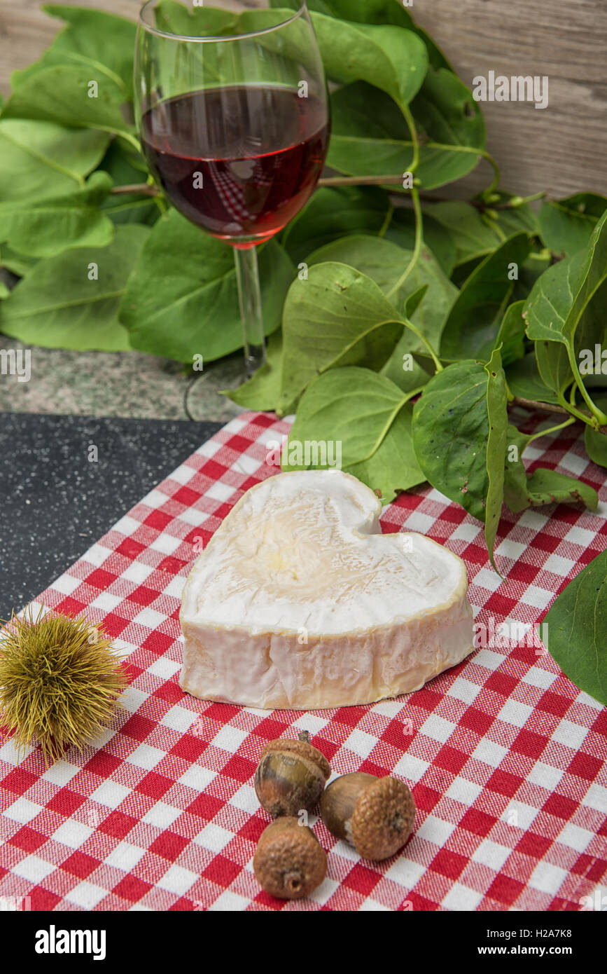 Neufchatel Käse auf eine rot-weiße Tischdecke mit Glasse Wein Stockfoto