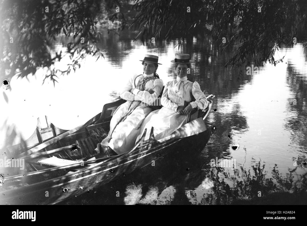 Zwei Frauen posieren auf einem Ruderboot auf einem Fluss-1900. Foto von Tony Henshaw Stockfoto
