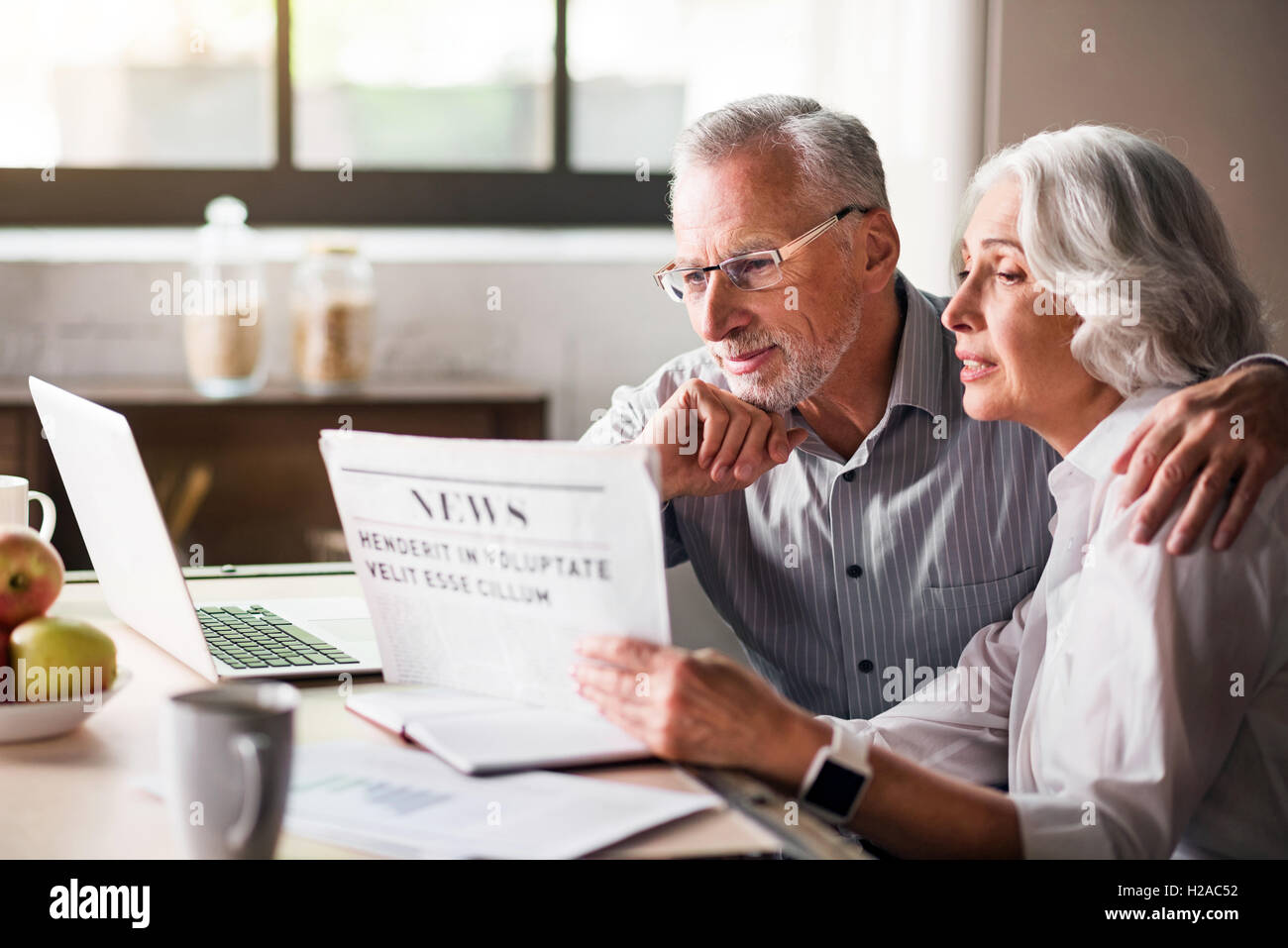 Glücklich und fürsorglichen altes Ehepaar Zeitunglesen in der Küche Stockfoto