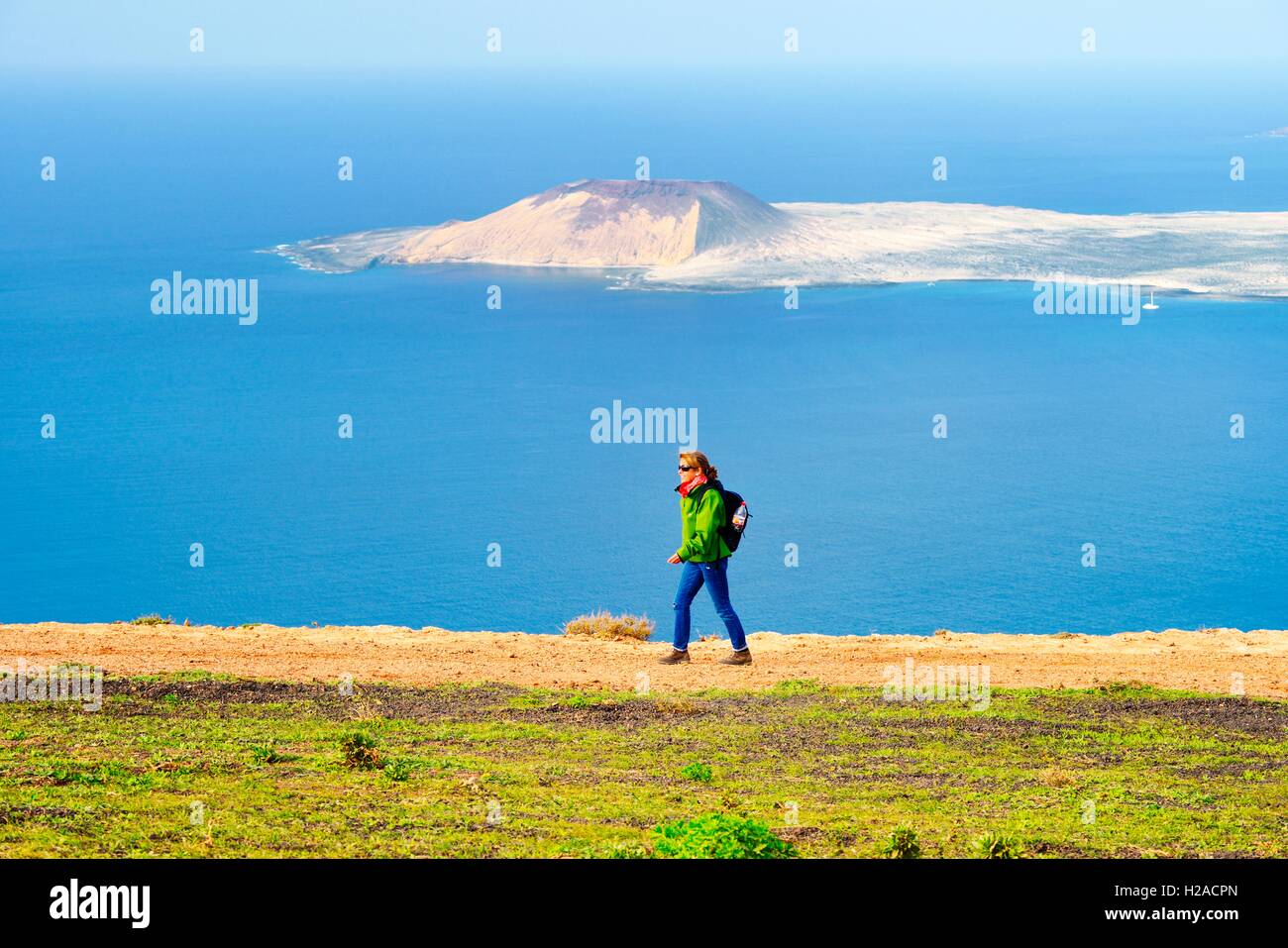 Lanzarote, Kanarische Inseln. Frau wandern Klippen von Risco de Famara bei Guinate 550 m über dem Atlantik. Isla Graciosa im Abstand Stockfoto