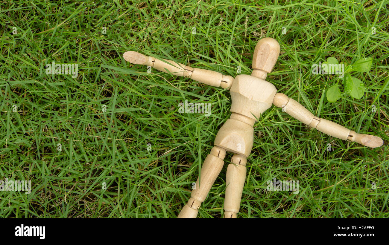 menschlichen Holzfigur legen auf Grasgarten entspannen Stockfoto