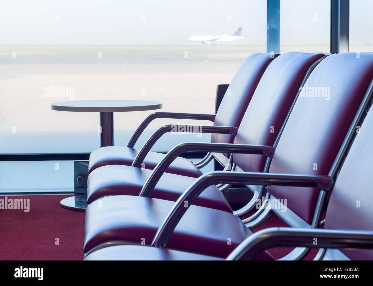 Bank im Abflug Flüge Wartehalle am Flughafen mit Flugzeug im Hintergrund Stockfoto