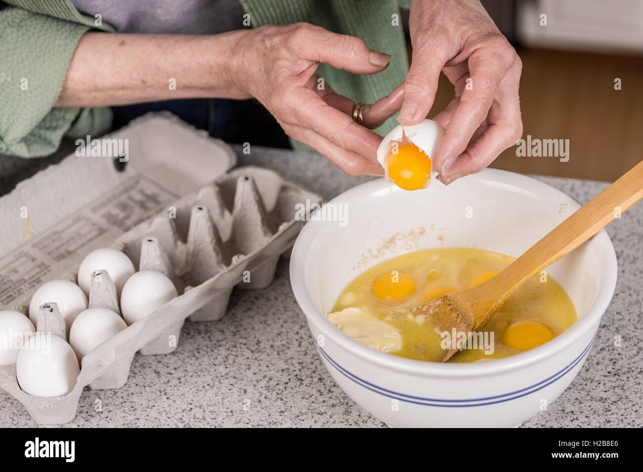 Frau bricht ein Ei nur das Eigelb zu den anderen Bestandteilen der Affe  Brot hinzufügen Stockfotografie - Alamy