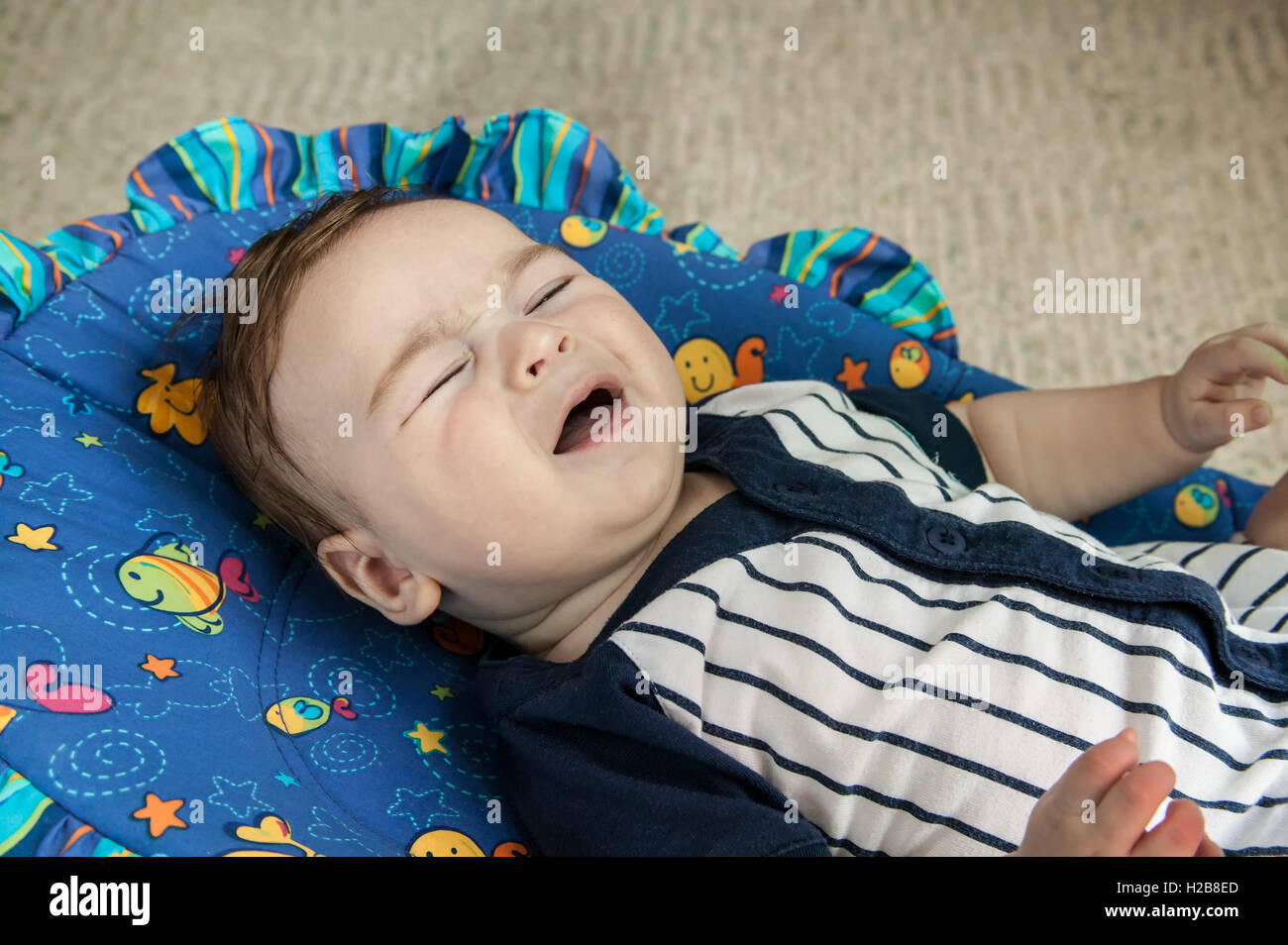 Unglücklich vier Monate altes Babyjungen Weinen liegen in einem Schaukelstuhl Sitz abgeholt werden wollen Stockfoto
