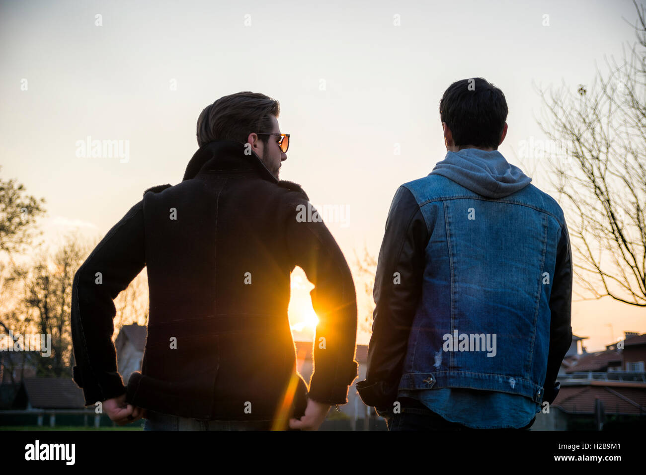 Zwei schöne lässig trendige junge Männer, 2 Freunde in einem städtischen Park zu Fuß und im Chat zusammen Stockfoto
