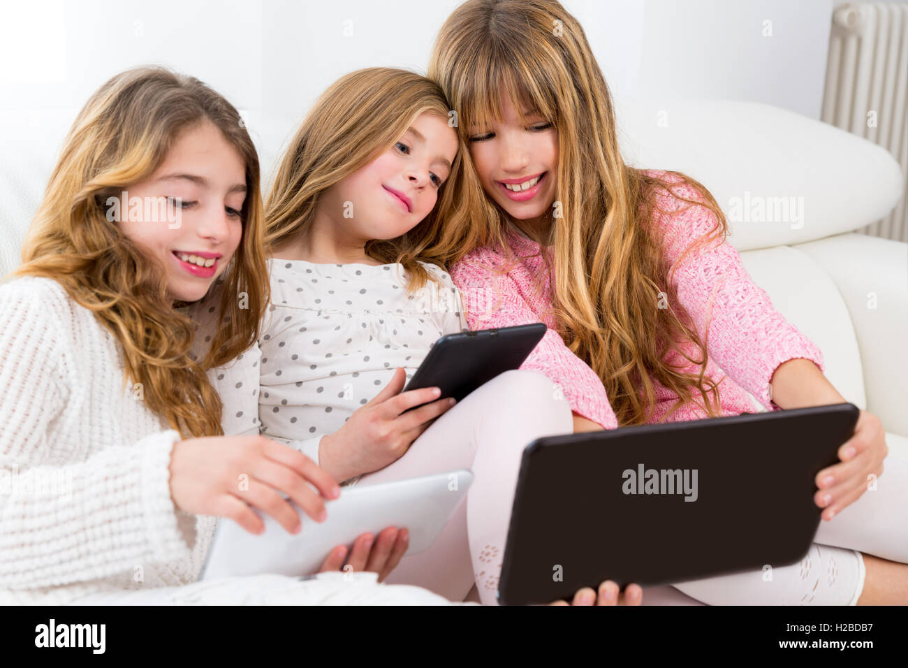drei junge Schwester Freundesgruppe Mädchen spielen zusammen mit Tisch Stockfoto