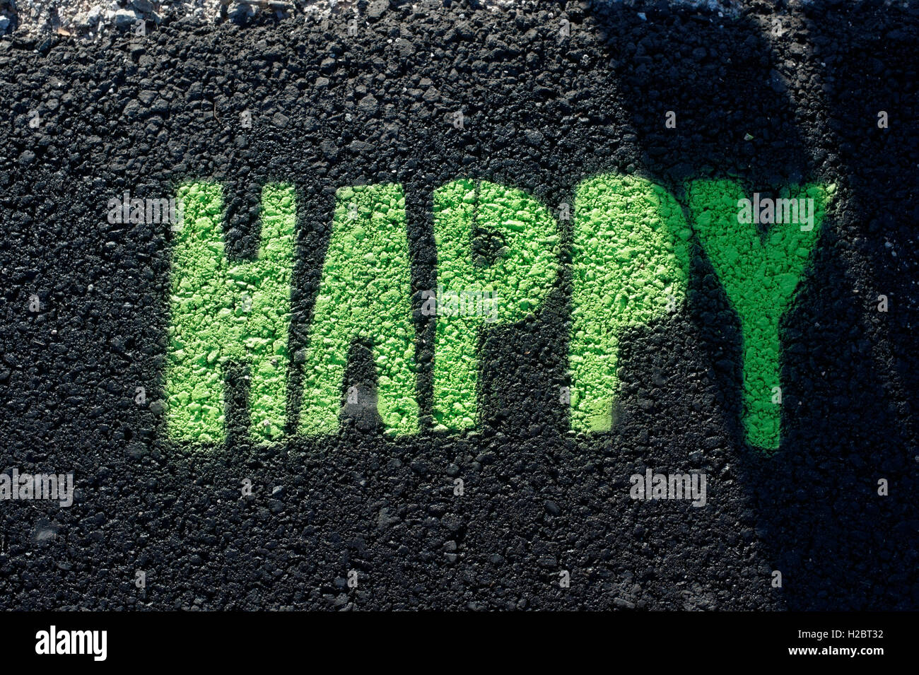 Grüne glücklich Graffiti gemalt auf einer schwarzen Asphaltstraße Stockfoto