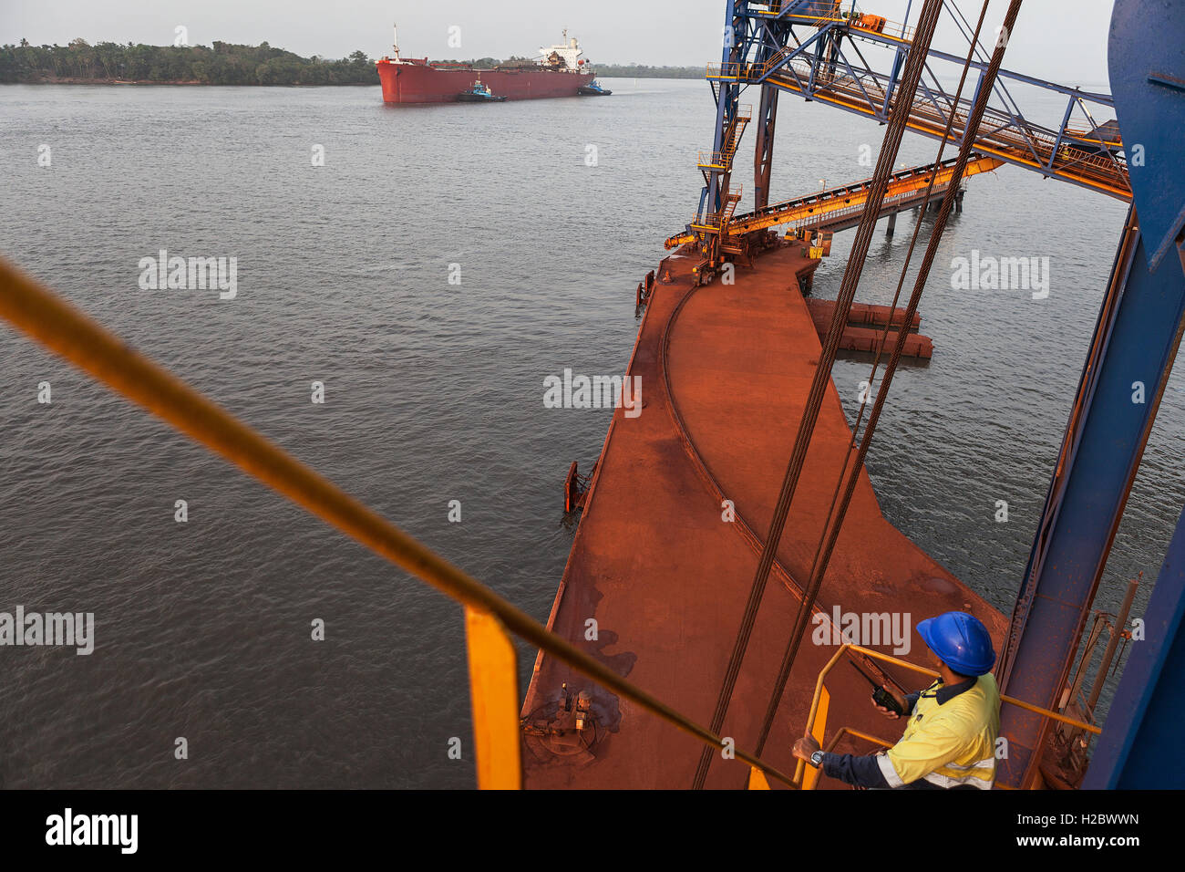 Marine und Hafen von Steg. Zwei Schlepper bewegen und drehen Frachtschiff, bevor Schiff Mauren und Anlegeplätze an der Anlegestelle und ist mit Eisenerz geladen. Stockfoto