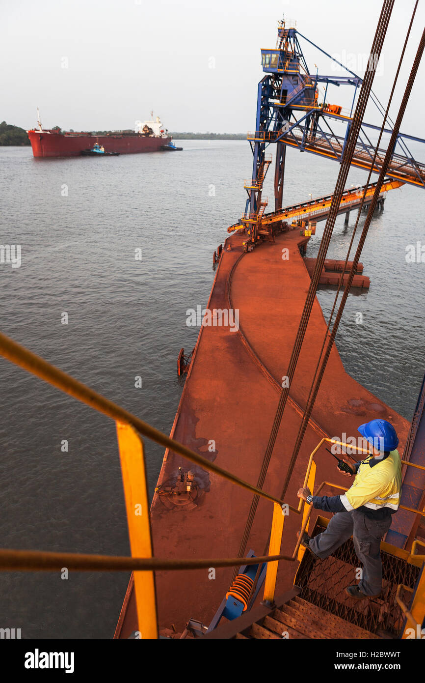 Marine und Hafen von Steg. Zwei Schlepper bewegen und drehen Frachtschiff, bevor Schiff Mauren und Anlegeplätze an der Anlegestelle und ist mit Eisenerz geladen. Stockfoto