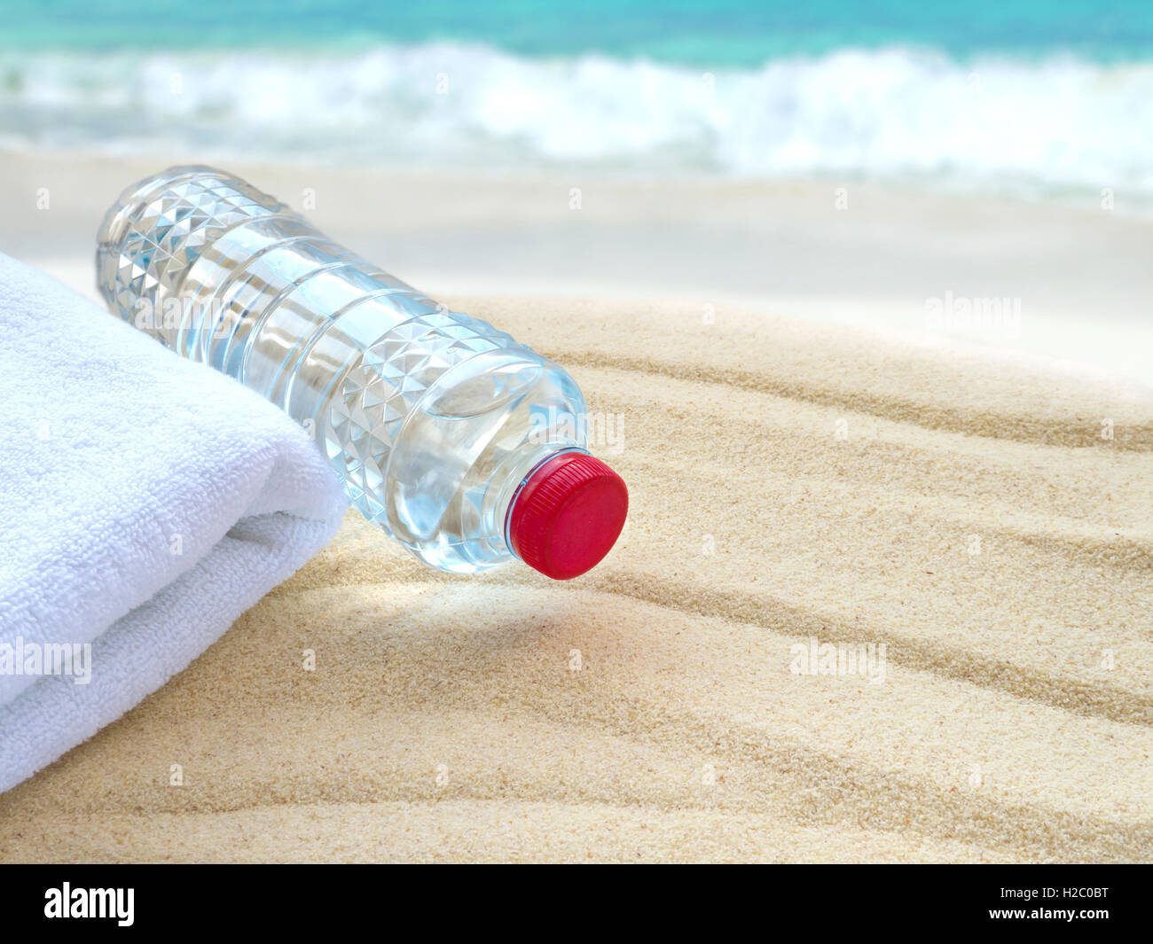 Mineralwasserflasche und ein Handtuch am Strand Stockfoto