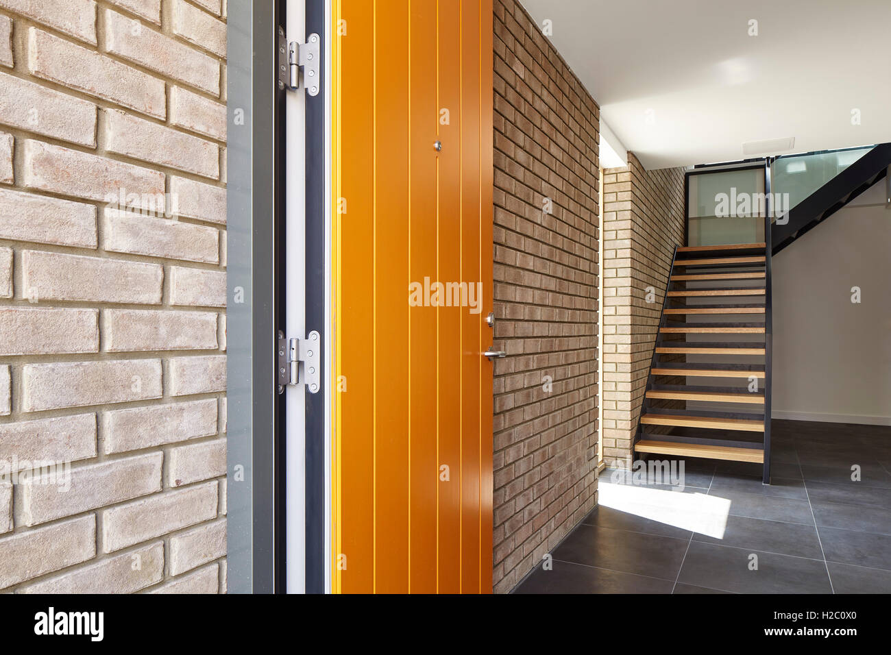 Orange Türöffnung in der Halle mit Treppe. Peel Place, London, Großbritannien. Architekt: Dexter Moren Associates, 2016. Stockfoto