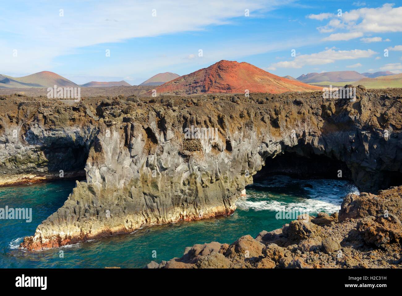Lanzarote, Kanarische Inseln. Abgefressenen vulkanischen Meer Höhlen Klippen von Los Hervideros und Lava Kegel Landschaft des Timanfaya-Nationalparks Stockfoto