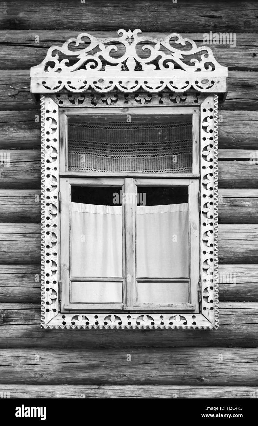 Die traditionelle ländliche russische alte Architektur Details. Fenster mit geschnitzten Holzrahmen in Mauer aus groben Protokolle, schwarz und wh Stockfoto
