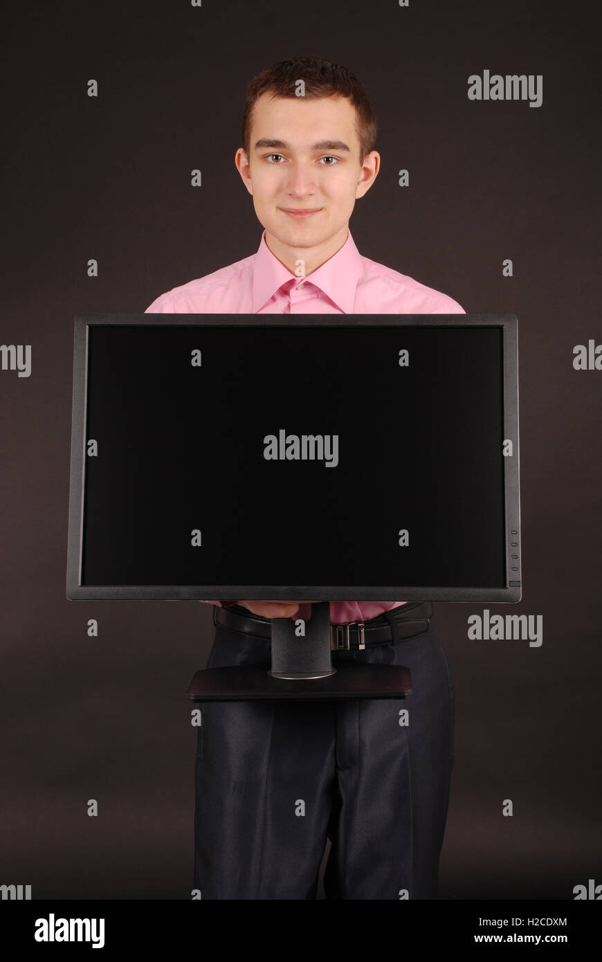 Glückliche junge Mann hält einen PC-Monitor auf schwarz isoliert Stockfoto