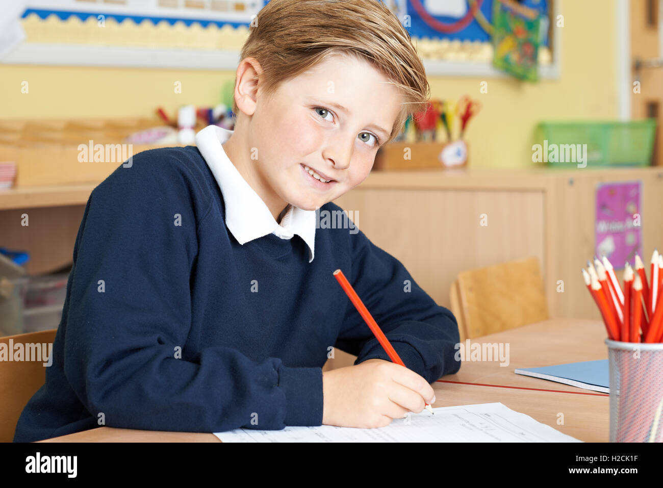Männliche Grundschule Schüler arbeiten am Schreibtisch Stockfoto