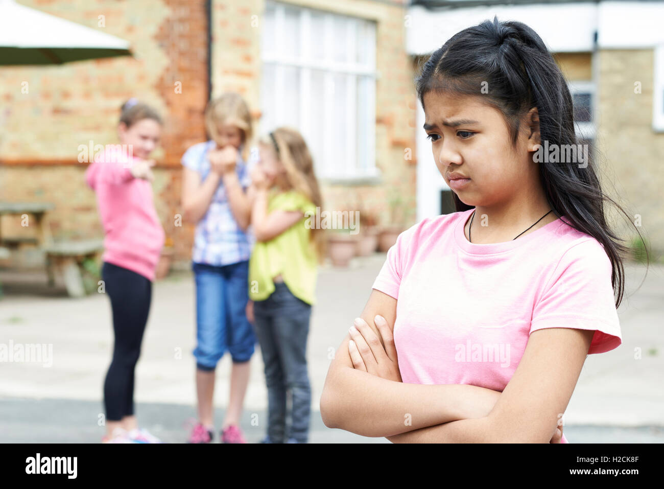 Unglückliche Mädchen wird durch Schulfreunde über geplaudert Stockfoto