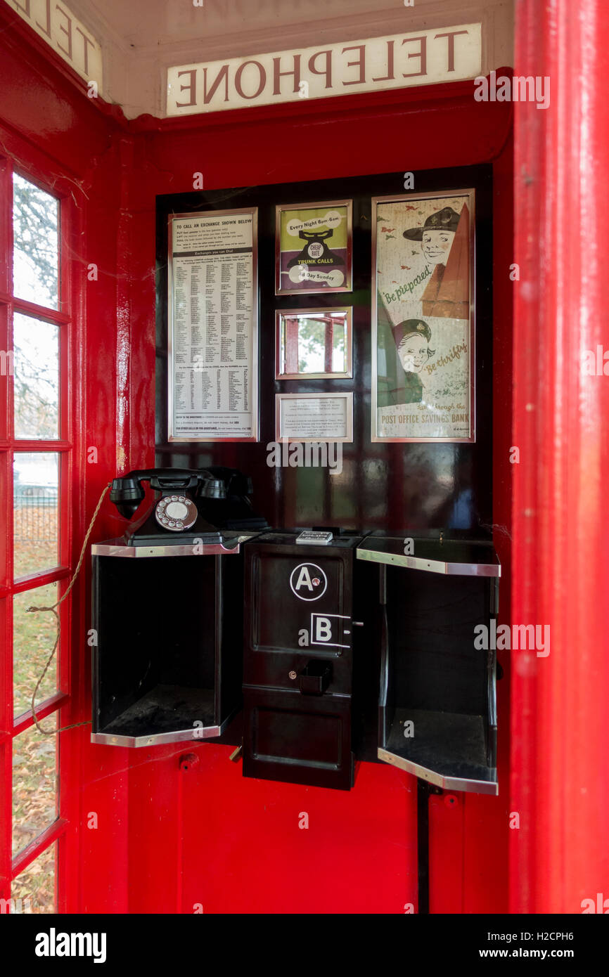 Innenraum der 1930er Jahre traditionelle britische rotes Telefon mit dem ursprünglichen Telefon Ausstattung und Poster. Stockfoto