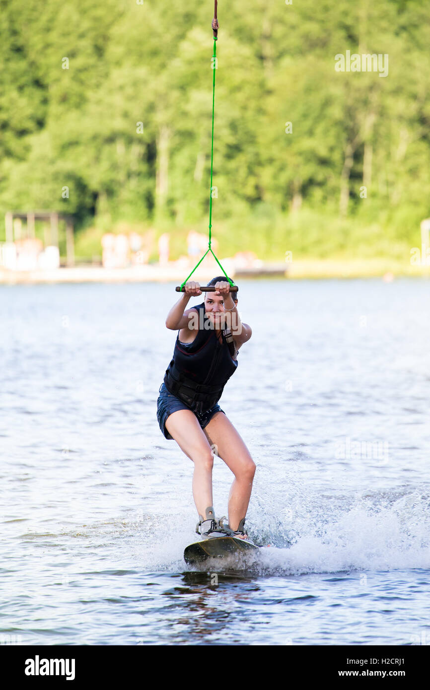 Junge Frau Studie Wakeboard fahren, an einem See Stockfoto