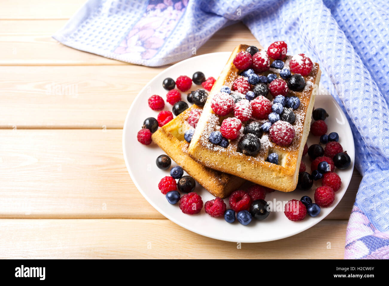 Weiche Waffel mit Heidelbeeren und Himbeeren auf blauem Leinen-Serviette. Frühstück weiche Waffeln mit frischen Beeren Stockfoto