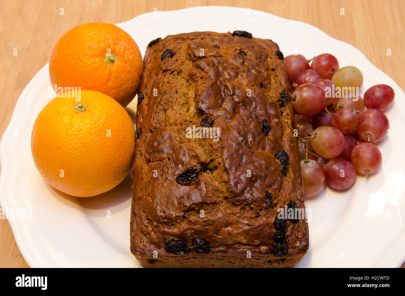 Bananenbrot auf weißen Teller mit Orangen und Trauben Stockfoto