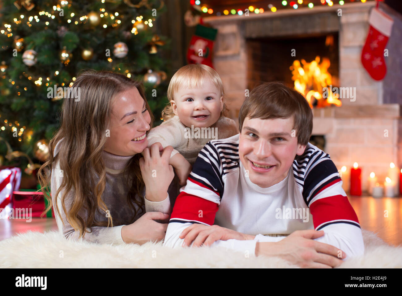 Glückliche Eltern und Kind viel Spaß in der Nähe von Weihnachtsbaum zu Hause. Vater, Mutter, Sohn Silvester feiern Stockfoto