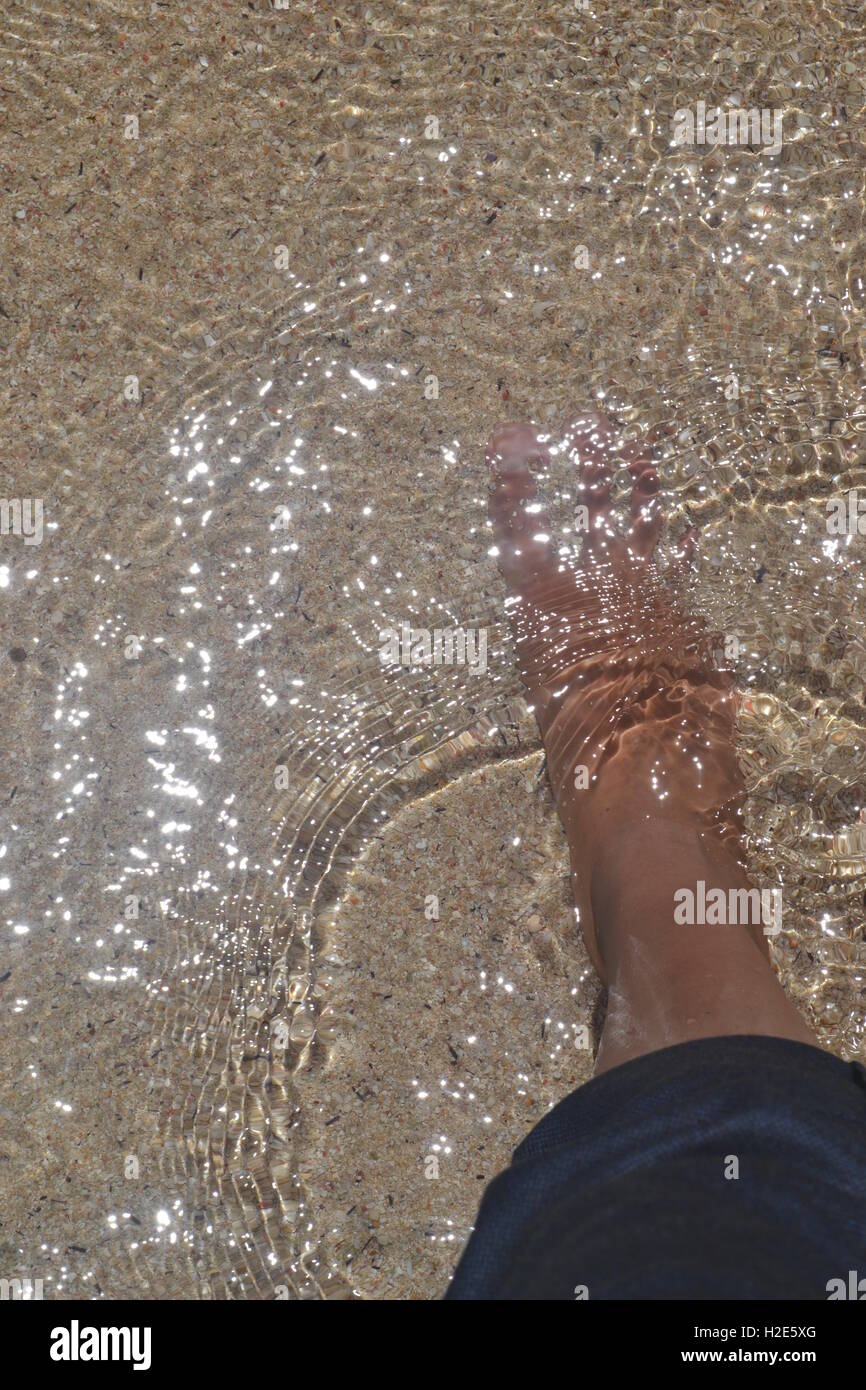 Füße im Meer mit Reflexion der Sonne Stockfoto