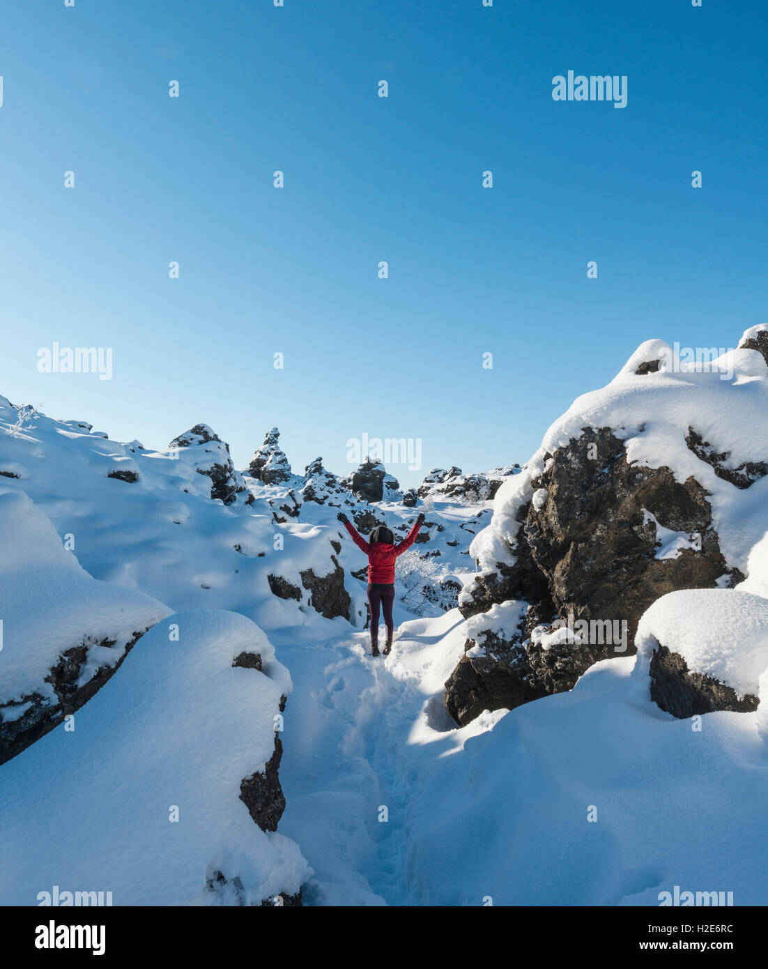 Frau mit Armen in der Luft, verschneite Landschaft, Lavafeld bedeckt mit Schnee, Krafla Vulkansystem Dimmuborgir Nationalpark Stockfoto
