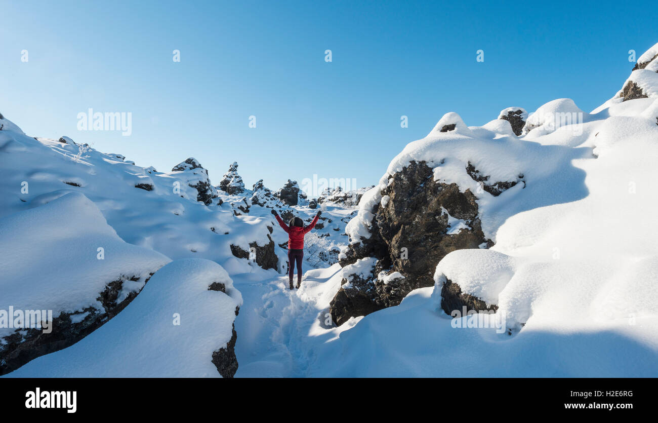 Frau mit Armen in der Luft, verschneite Landschaft, Lavafeld bedeckt mit Schnee, Krafla Vulkansystem Dimmuborgir Nationalpark Stockfoto