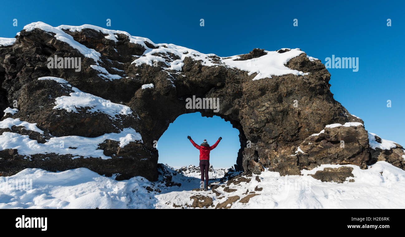Frau, die in einem natürlichen Bogen Lavafeld mit Schnee bedeckt, Krafla Vulkansystem, Dimmuborgir Nationalpark, Mývatn Stockfoto