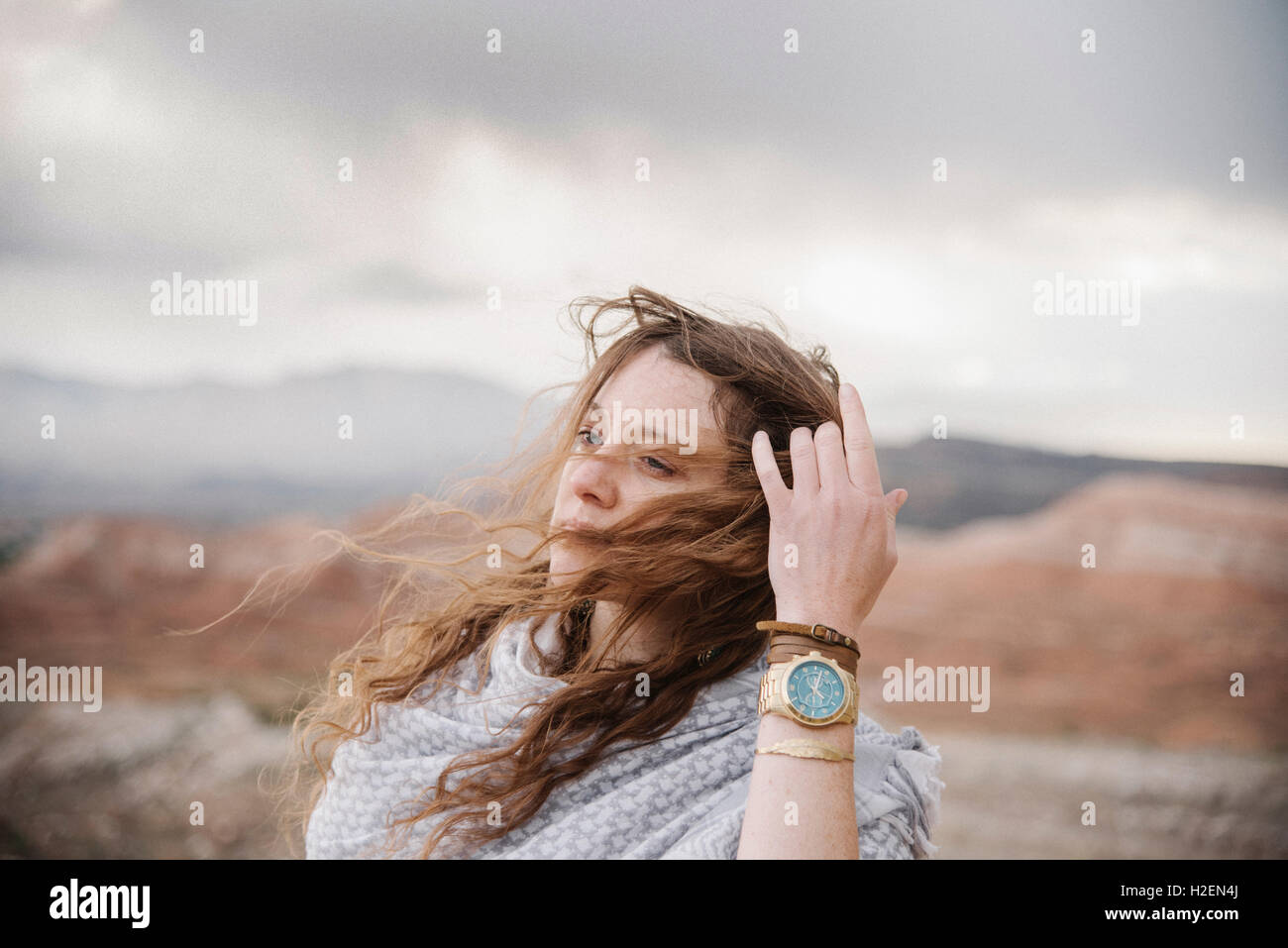 Eine Frau mit Lon g Haare wehen im Wind stehen in einer Wüstenlandschaft. Stockfoto