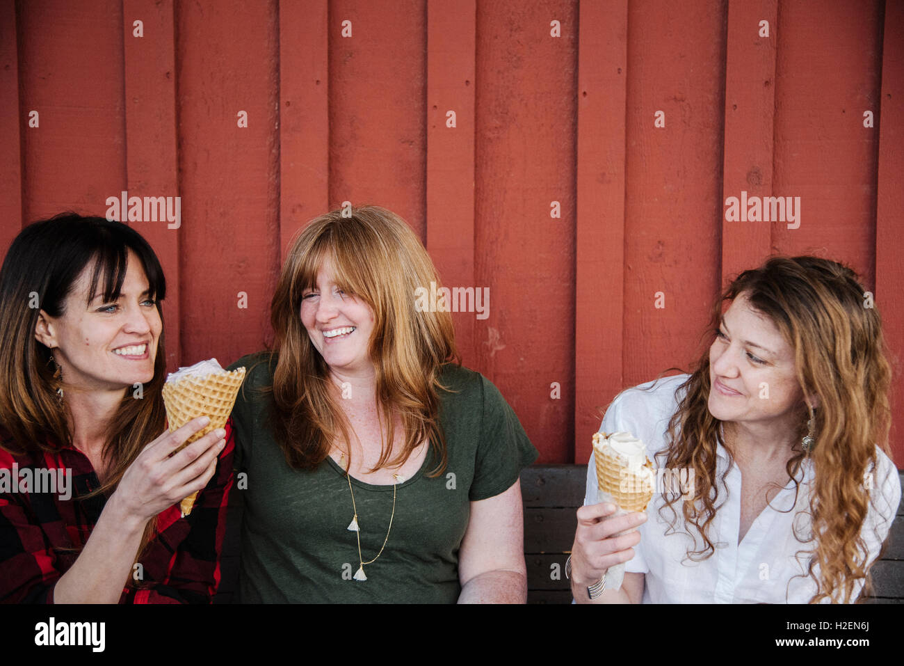 Drei Frauen sitzen auf einer Bank, Eis essen. Stockfoto
