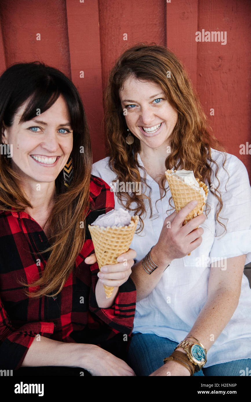 Zwei Frauen sitzen auf einer Bank, Eis essen. Stockfoto