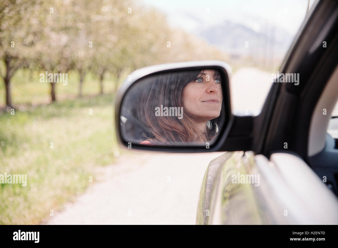 Frau in einem Auto auf einem Roadtrip, Reflexion in den seitlichen Spiegel gesehen. Stockfoto