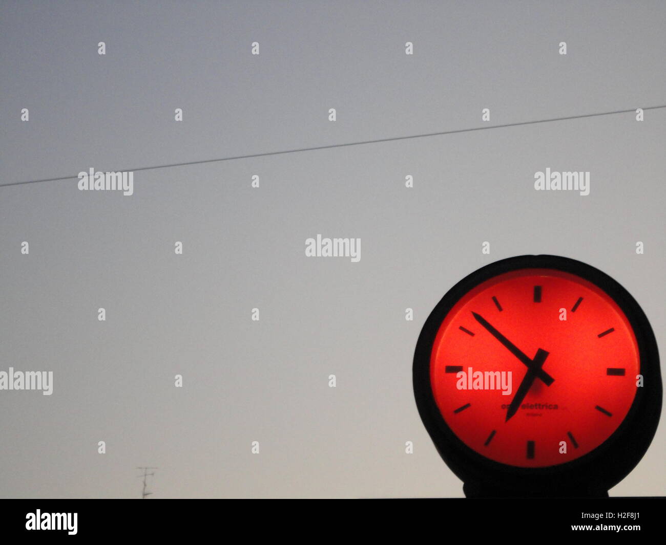 Spaß funky Leuchtstoffröhren beleuchtet rote Uhr gegen ein strahlend blauer Himmel bei Dämmerung, Mailand Stockfoto