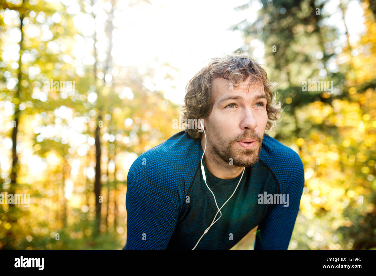 Junge hübsche Läufer mit Kopfhörer außerhalb im Herbst Natur Stockfoto