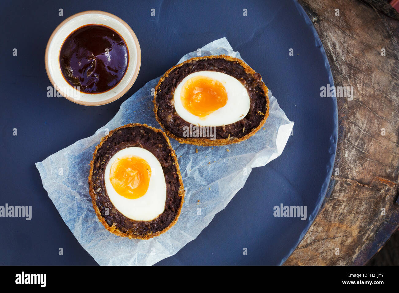 Dorf Pub Essen. Eine blaue Schale mit einem frisch gemachten Scotch Ei schneiden zwei und einen Topf mit Soße. Stockfoto