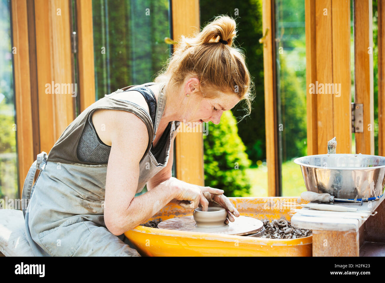 Eine Frau Töpfer arbeiten Ton auf einer Töpferscheibe in ihrer Werkstatt. Stockfoto