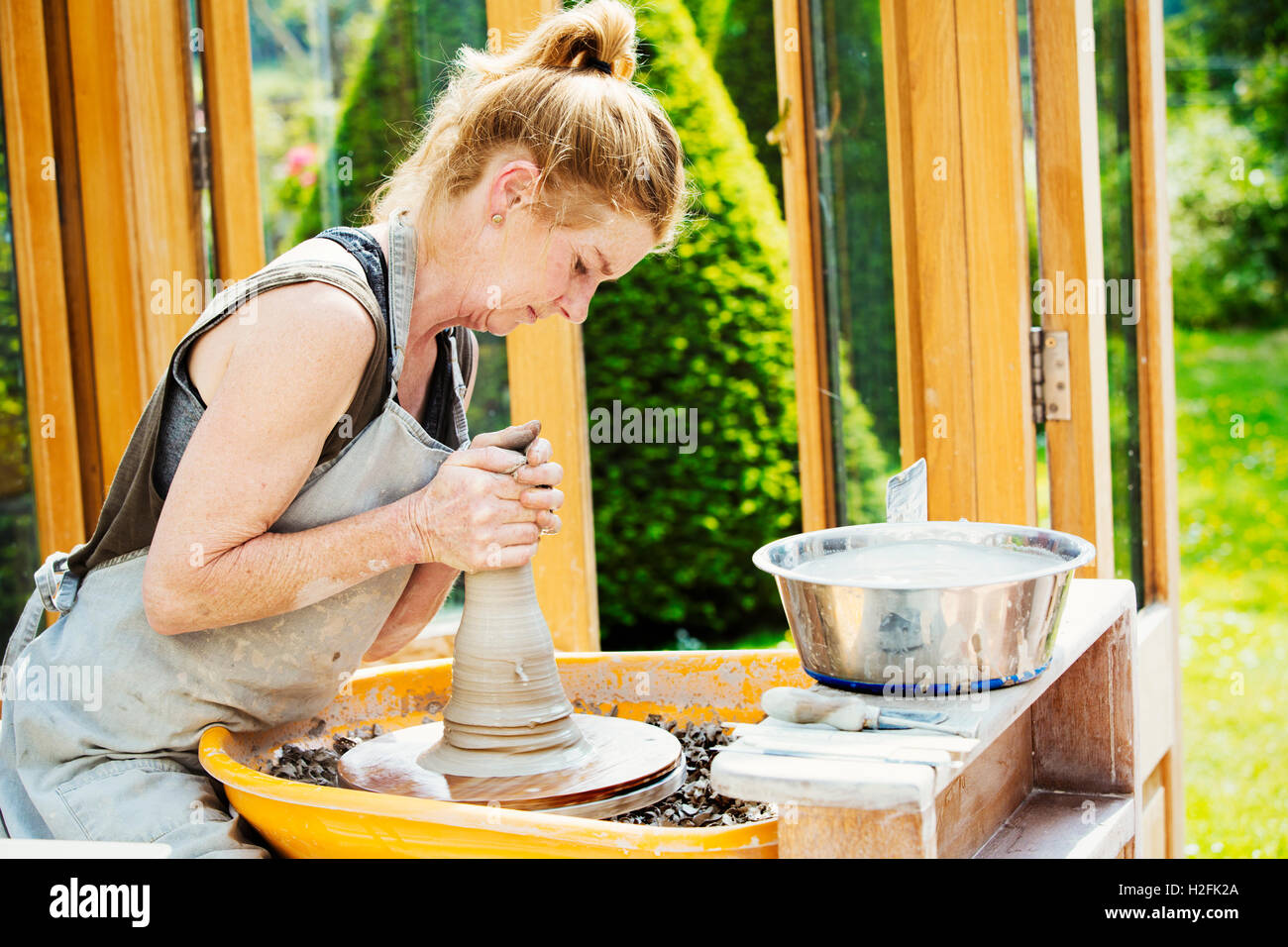 Eine Frau Töpfer arbeiten Ton auf einer Töpferscheibe in ihrer Werkstatt. Stockfoto