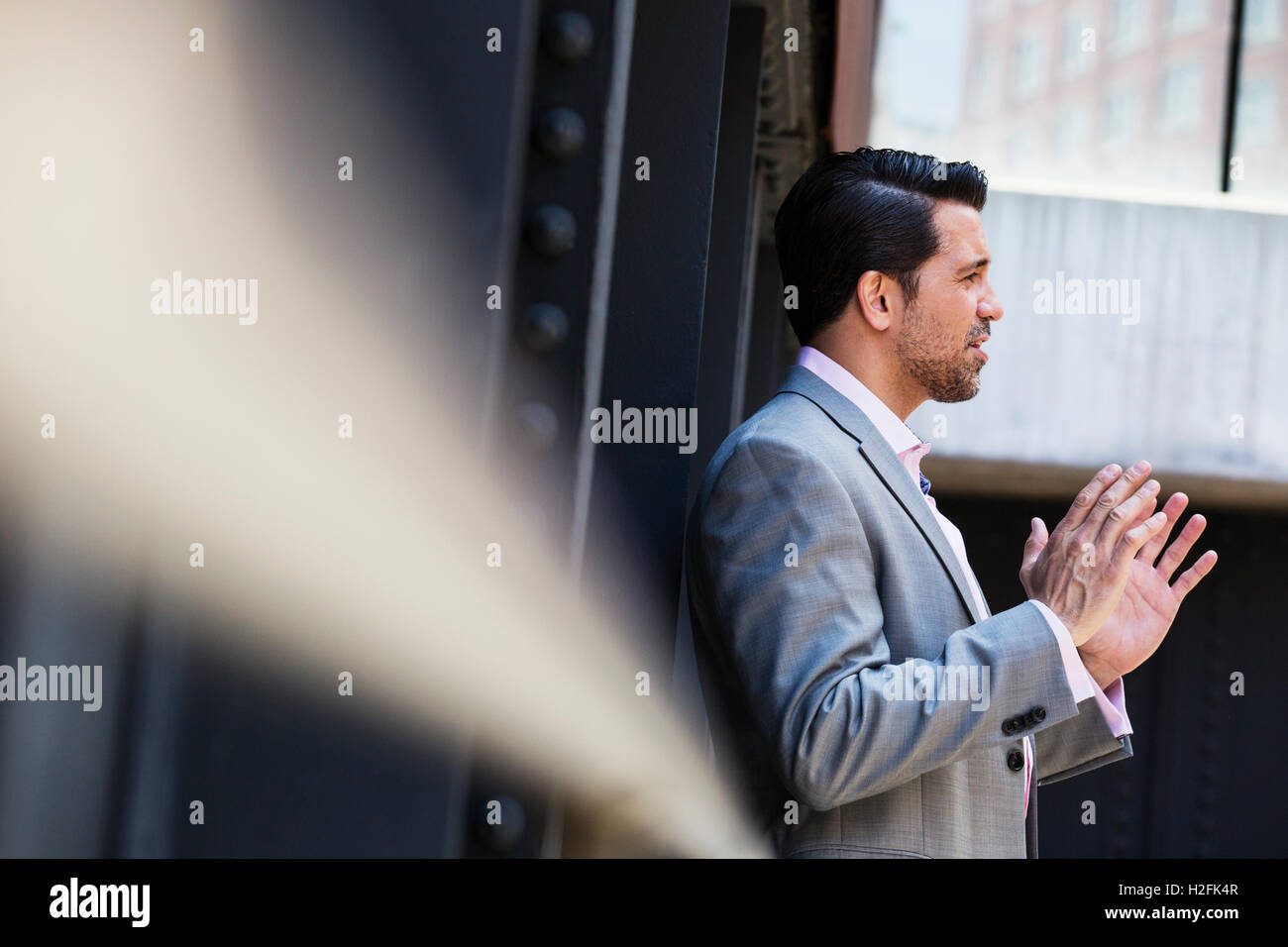 Geschäftsmann trägt einen grauen Anzug stehen im Freien, sprechen und Gestikulieren mit den Händen angehoben. Stockfoto