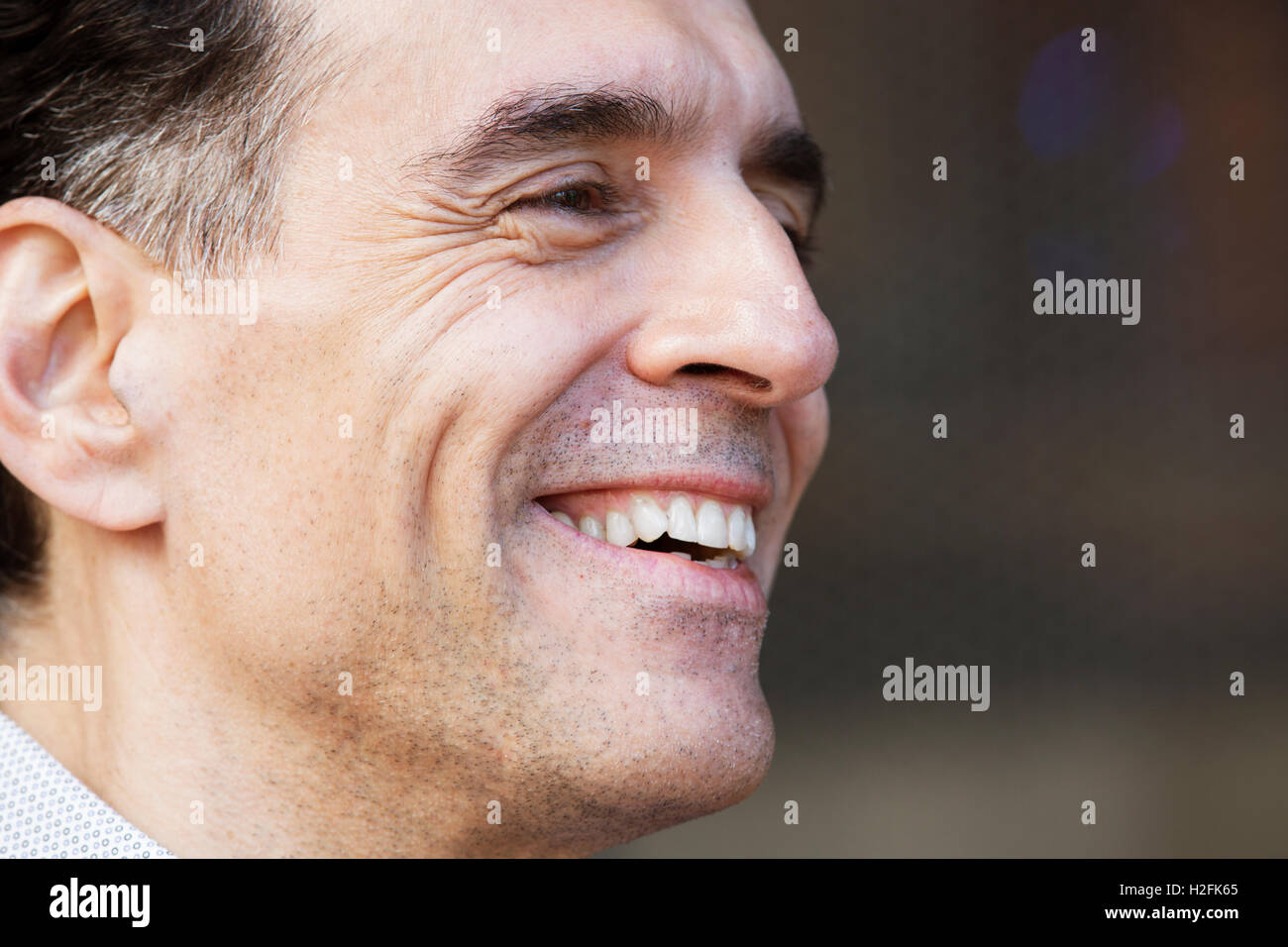 Ein Mann mit Ergrauen der Haare in einem Hemd, seitlich suchen, lächelnd. Stockfoto