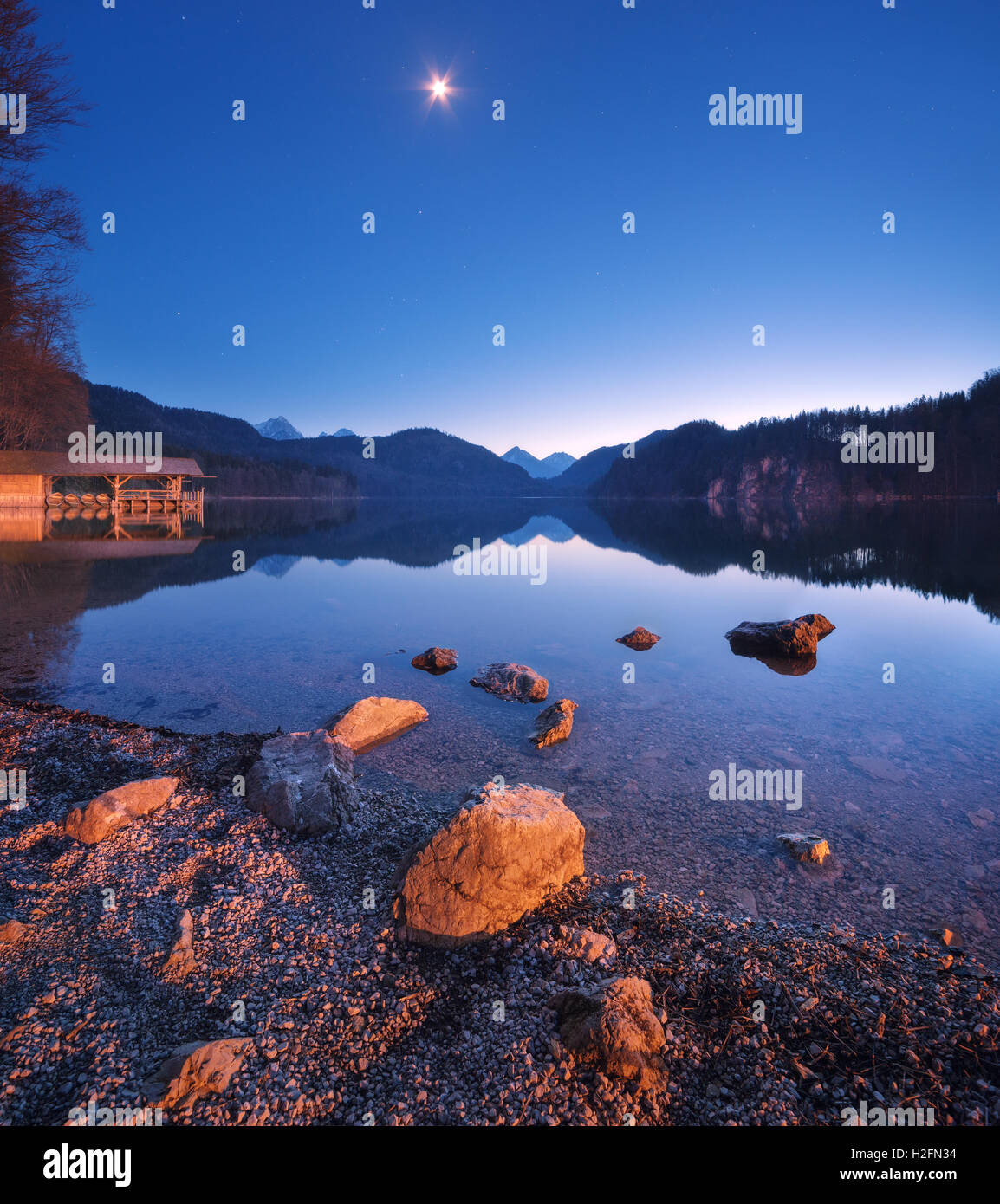 Alpsee See in Deutschland in der Nacht im Frühjahr. Schöne Nachtlandschaft mit See, Berge, Wald, Sterne, Vollmond, Himmel und sto Stockfoto