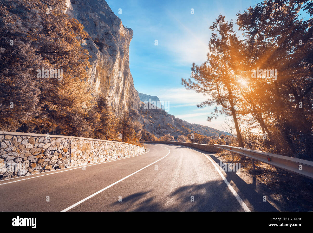 Asphaltierte Straße. Bunte Landschaft mit schönen Bergstraße mit perfekter Asphalt. Hohe Felsen, blaue Himmel bei Sonnenaufgang im Sommer. Stockfoto