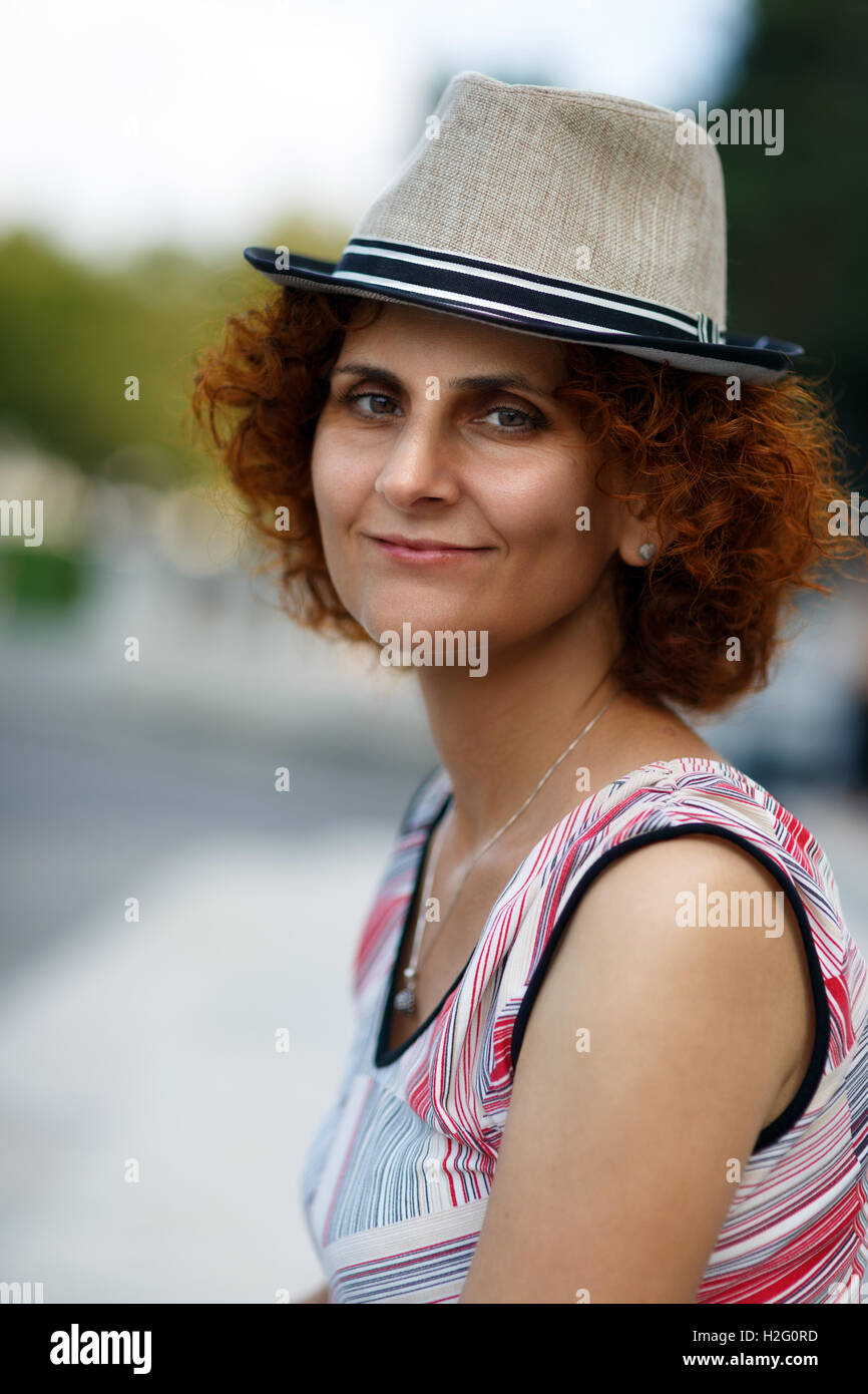 Nahaufnahme einer rothaarige Frau mit Hut in einem städtischen Umfeld Stockfoto