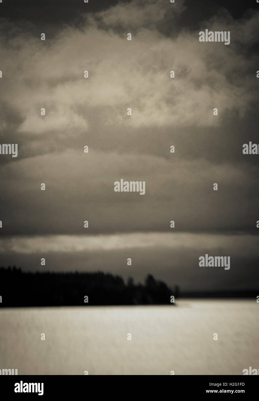 Verschwommene dunkle Landschaft mit See und Silhouette des Waldes. Launisch und ominösen Natur Szene, Schweden. Stockfoto