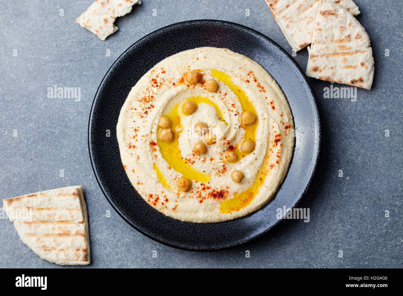 Hummus, Kichererbsen dip, mit Gewürzen und Pita, Fladenbrot in einer schwarzen Platte. Ansicht von oben Stockfoto